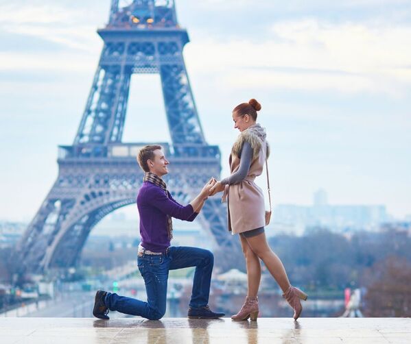 Man on bended knee proposing to woman in front of Eiffel Tower